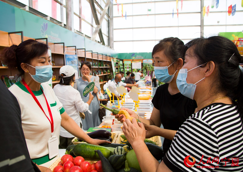 參觀者向參展人員詢問蔬菜品種。蘇暢攝
