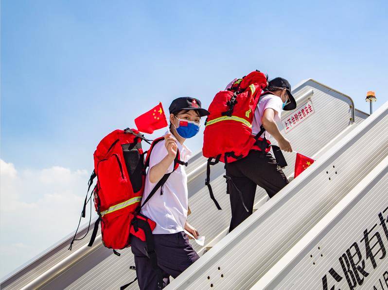 登機的醫療隊員向送行人員致意。 人民網 張海峰攝