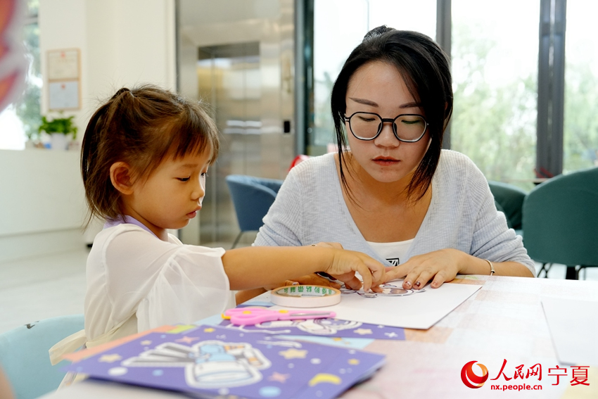 7月23日，寧夏銀川市未來社區“暑托班”里，老師正在教小朋友剪紙。人民網記者 閻夢婕攝
