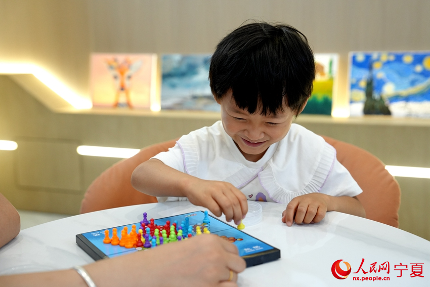 7月23日，寧夏銀川市居安家園社區“暑托班”里，小朋友和老師下棋。人民網記者 閻夢婕攝