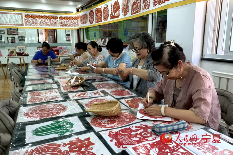 長城花園社區居民正在社區活動室內剪紙。人民網記者梁宏鑫攝